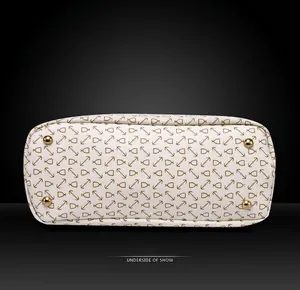 Underside of white handbag with gold anchor print and four protective metal feet