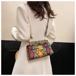 Detail of colorful python pattern crossbody bag with gold lock on white blazer
