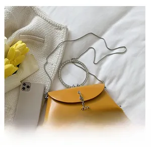 Detail of yellow handbag with rhinestone circular handle and elegant metal U-buckle