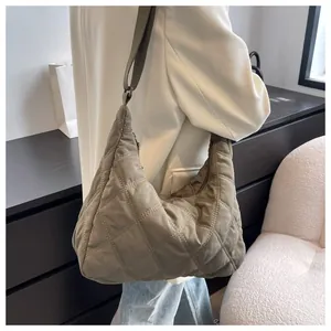 Detail einer khakifarbenen Stepptasche mit Rautenmuster, die an der Schulter hängt