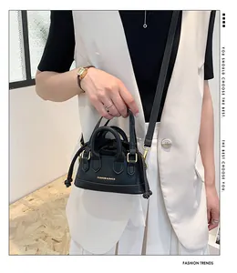 Detail of a mini black leather crossbody bag with drawstring closure and golden hardware