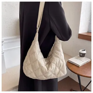 Detail einer großen gesteppten Hobo-Tasche in Creme mit Rautenmuster und verstellbarem Gurt