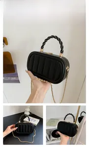 Détail d'un sac boîte noir matelassé avec chaîne dorée et poignée tressée chic