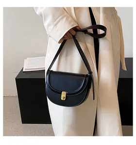 Detail of a black PU saddle bag featuring a textured finish and golden buckle closure