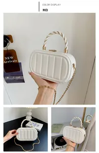 Détail d'un sac boîte blanc cassé avec texture verticale et poignée en métal torsadé