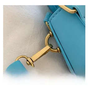 Detailed close-up of premium gold-tone metal buckle on light blue faux leather bag