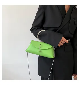 Sac gelée vert avec poignée en perles et bandoulière sur un blazer noir