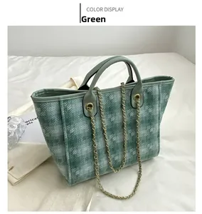 Close-up of green tweed tote bag featuring quilted texture and chain strap detail