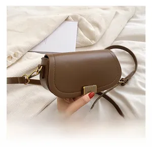 Detail of a brown semi-circular saddle bag with golden metal clasp on velvet fabric