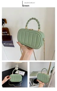 Détail du sac capsule vert clair avec rayures verticales et poignée tressée