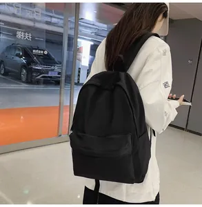 Side view of a black waterproof nylon backpack on a model showing large front pocket