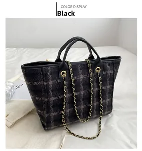 Detail of black plaid tweed tote bag with leather handles and gold metal chain strap