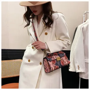 Detail of multi-color snakeskin texture crossbody bag with gold buckle on female model