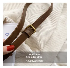Adjustable brown leather shoulder strap detail with vintage gold buckle on white fabric
