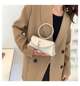 Détail du sac crème élégant avec une poignée circulaire en strass et une chaîne en métal