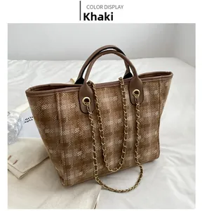 Detail of khaki bucket bag showing woven texture, brown leather trim and gold chain strap