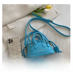 Mini sky blue crossbody bag shown next to a smartphone to demonstrate the small size