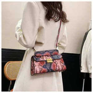 Detail of multi-color snakeskin texture and golden square buckle on a chic crossbody bag