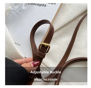 Detail view of brown leather strap featuring a polished gold adjustable buckle and stitching