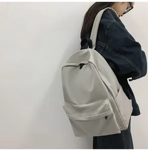 Macro detail of a light grey nylon backpack with side pockets and front zipper