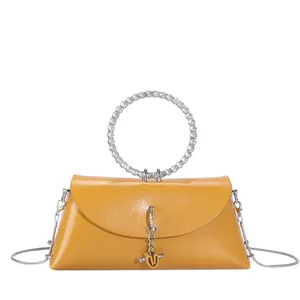 Gros plan du sac en cuir jaune brillant avec poignée ronde en métal sertie de strass
