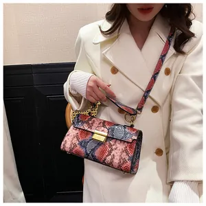 Detail of square snake print bag with gold twist lock on model in beige coat