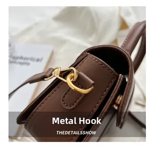 Close-up of premium gold hardware hook and precise stitching on brown leather handbag