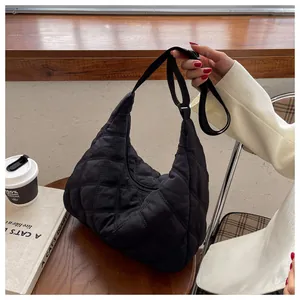 Detail der schwarzen Stepptasche mit verstellbarem Gurt in einem Café-Ambiente