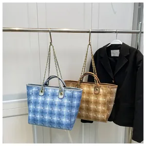 Detail view of large tote bags with geometric quilted texture and chain handles