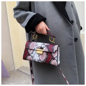 Detail shot of chic snakeskin pattern texture and golden square twist lock on small handbag