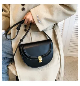 Detail of a black saddle bag with a rectangular gold buckle on a beige coat