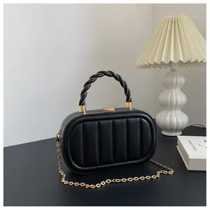 Détail du sac à main rigide ovale noir avec texture matelassée et chaîne dorée