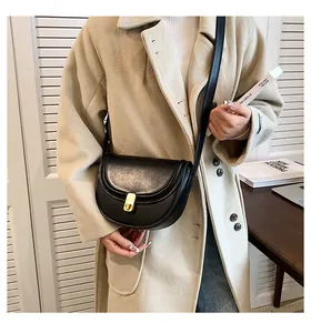 Detail of black PU leather saddle bag with gold buckle on beige coat for casual style