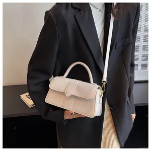 Detail of cream leather crossbody bag featuring geometric flap and gold hardware