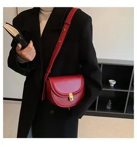Detail of red leather saddle bag with golden metal buckle on a black coat outfit