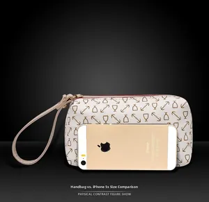 Detailed view of patterned wristlet bag with comparison to a smartphone for size reference