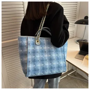 Detail of light blue bucket bag with woven texture and gold chain strap in office setting