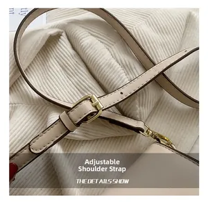 Detail view of the adjustable beige leather shoulder strap with gold metal hardware buckle