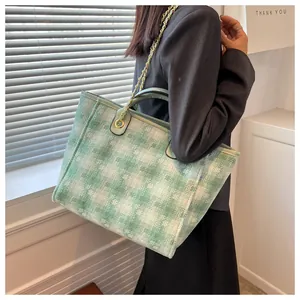 Detail of green and white geometric woven tote bag with gold chain and leather handle