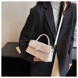 Detailed view of the cream rectangular handbag with a triangle flap and gold hardware