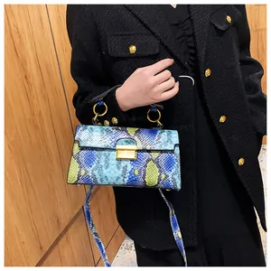 Detail of snake pattern shoulder bag with golden buckle and crossbody strap on tweed coat