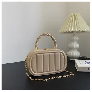 Détail de sac de soirée rigide beige avec texture verticale et poignée torsadée