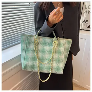 Detail of light green lattice tote bag with metallic chain and leather handle