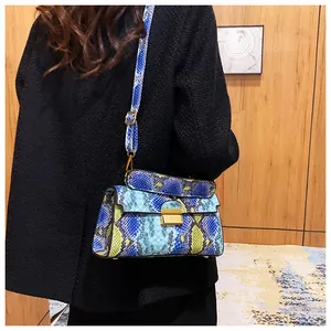 Model wearing a blue and yellow snake pattern crossbody bag with a gold metal clasp
