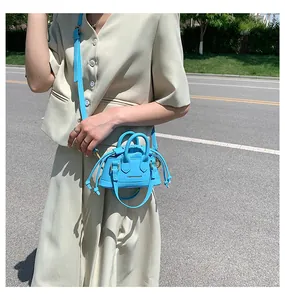 Close-up of sky blue mini crossbody bag with drawstring details on a beige suit