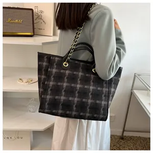 Detail of vintage plaid tote bag with metal chain strap and leather handle