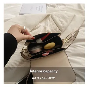 Internal capacity detail of beige saddle bag showing makeup items and metal buckle