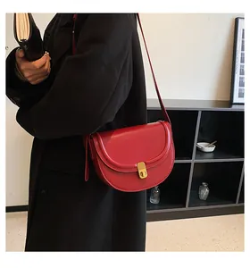 Detail of red faux leather saddle bag with gold metal buckle on black coat