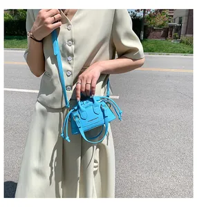 Detail of bright blue mini crossbody bag with drawstring closure and golden hardware