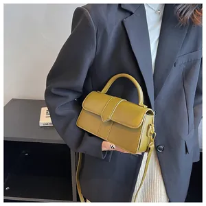 Detail view of olive green crossbody bag with leather texture on black blazer suit